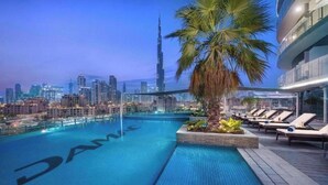 A rooftop pool with a view of the city skyline and the Burj Khalifa.