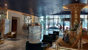 A modern lobby with a reception desk, seating area, and a large glass window.