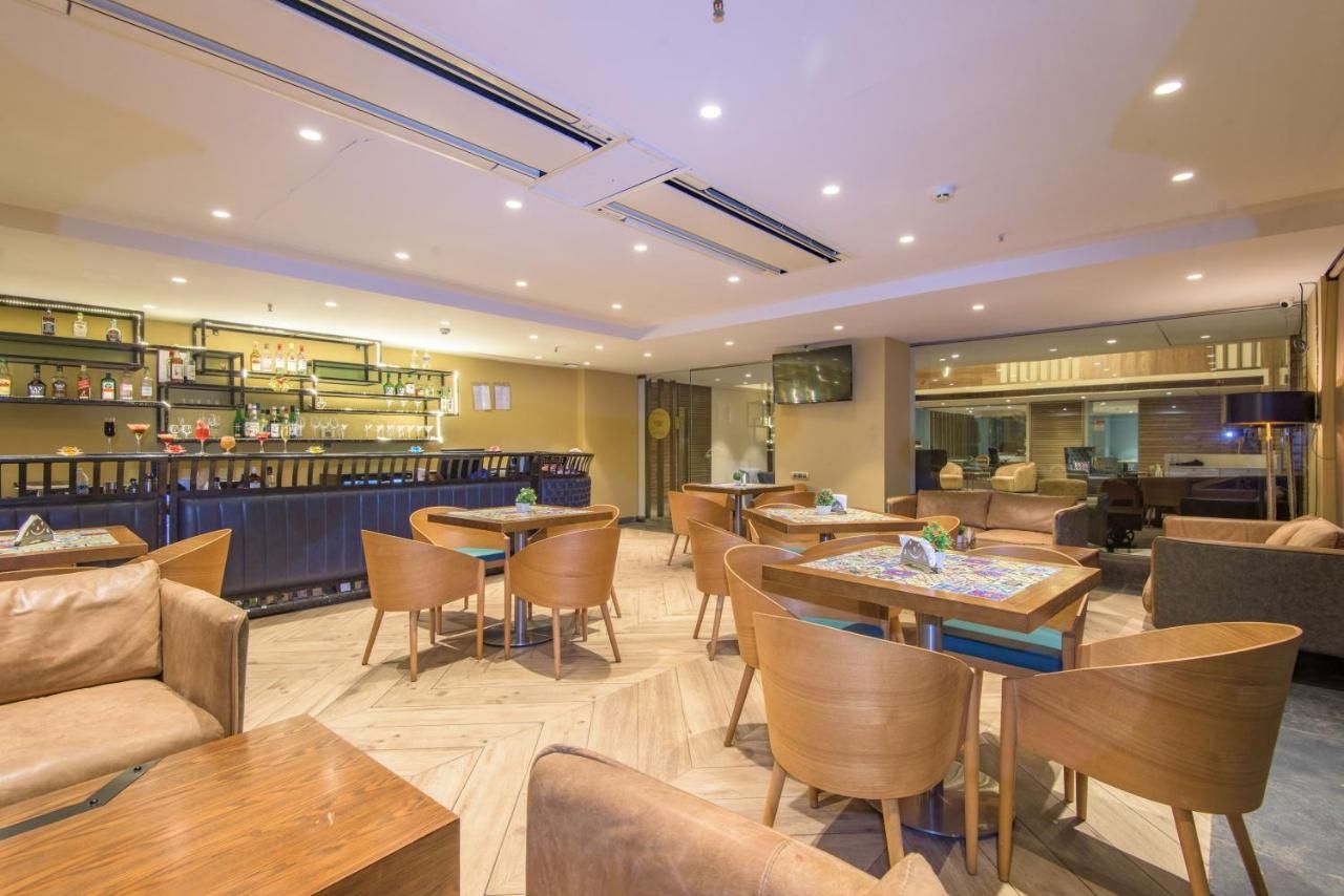 Un hall de hotel con área de bar, espacios para sentarse y una pantalla de televisión.
