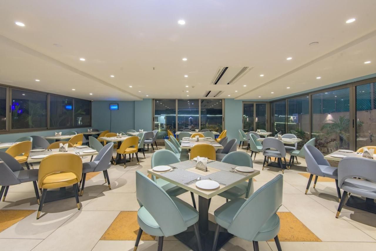 Un vaste espace dédié à la salle à manger, avec de nombreuses tables et chaises, de grandes fenêtres et un design moderne au niveau du plafond.