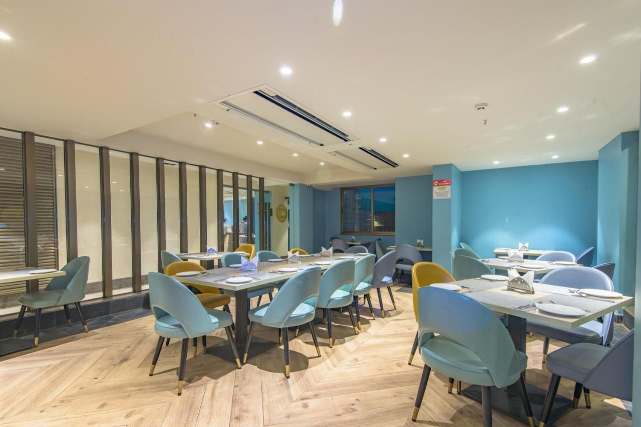 Un comedor moderno con varias mesas y sillas, ventanas amplias y una pared de acento azul.