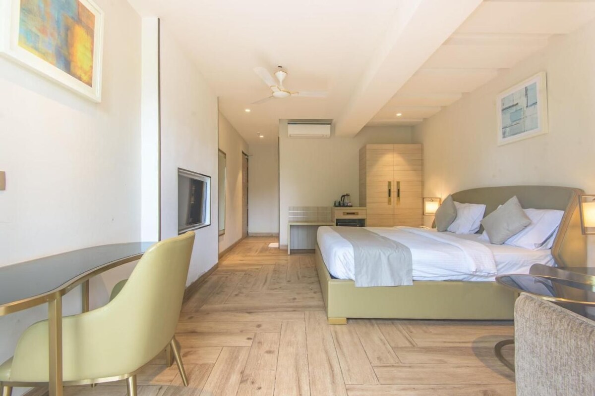 A bedroom with a bed, a desk, a chair, a television, and a ceiling fan.