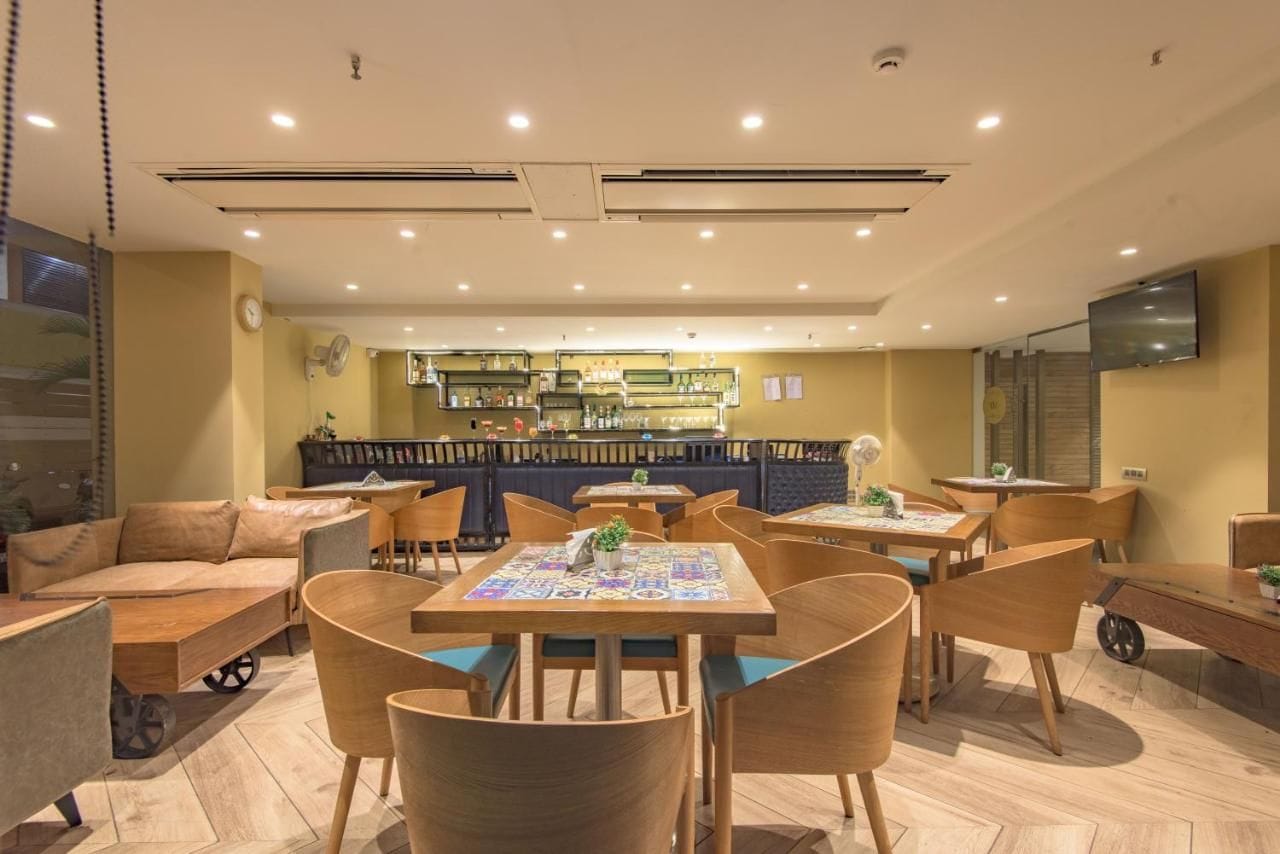 A restaurant with multiple tables and chairs, a bar area, and a seating area with sofas.