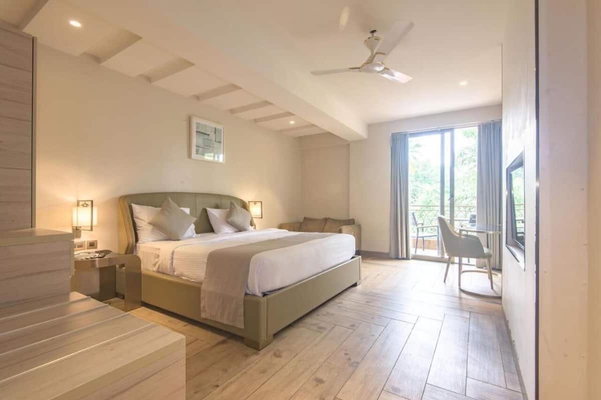 A bedroom with a bed, bedside tables, a ceiling fan, and a view through a glass door to the outside.