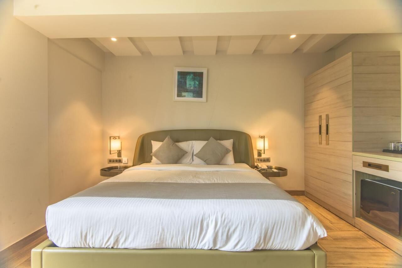 A bedroom with a bed, nightstands, a wall-mounted picture, and a built-in fireplace.
