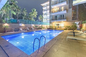 A swimming pool with a tiled edge, surrounded by lounge chairs and potted plants. - The Fern Residency, Calangute (Calangute)