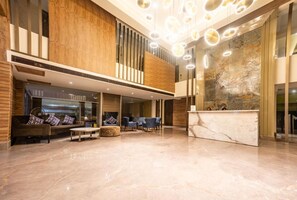 A spacious lobby with a reception desk, seating area, and a large wall with a textured design. - The Fern Residency, Calangute (Calangute)
