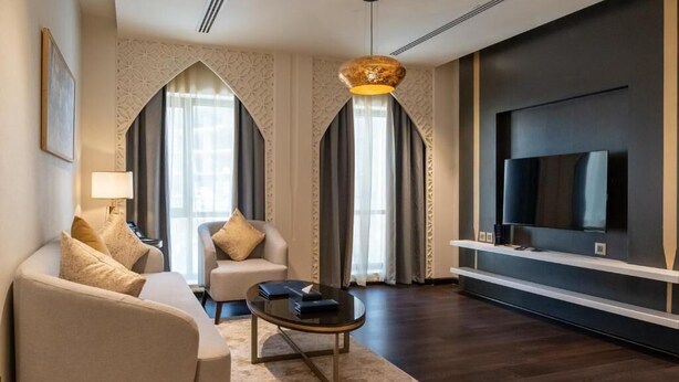 Una sala de estar moderna con un sofá, un sillón, una mesa de centro y un televisor de pantalla plana montado en la pared.