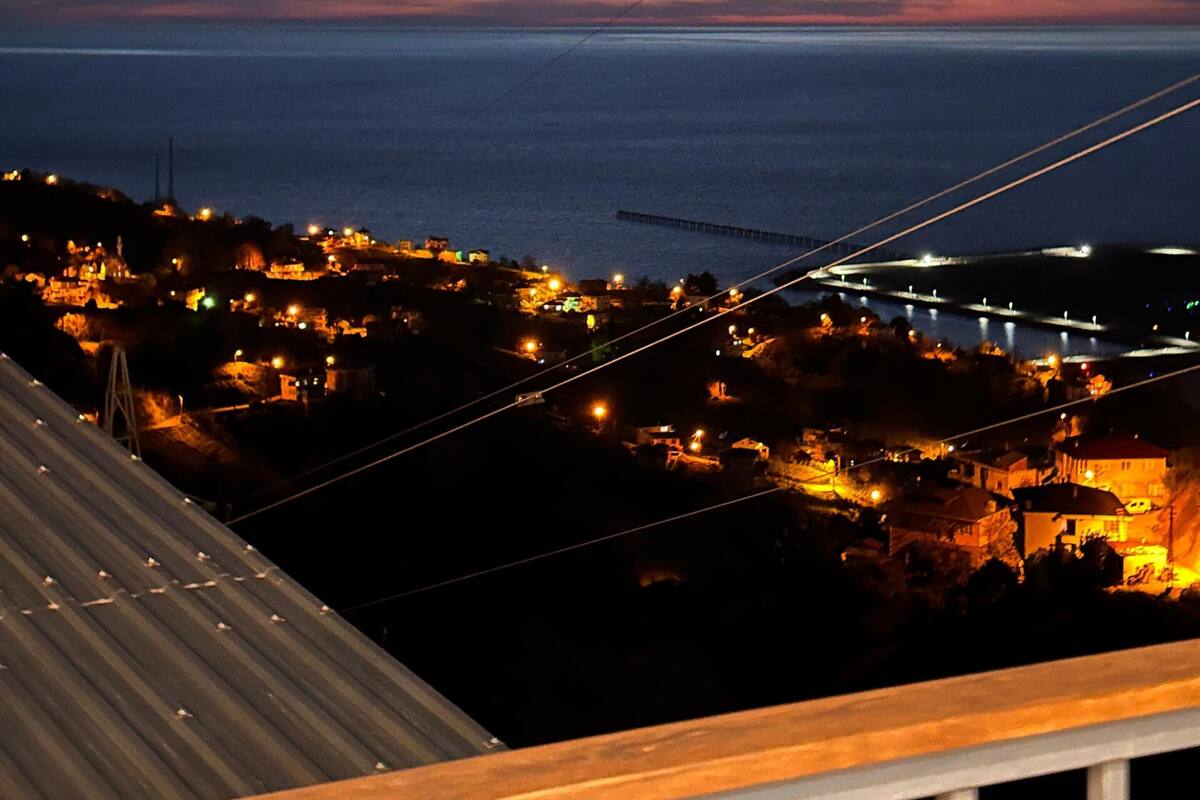 Eine Küstenstadt im Dämmerlicht mit Blick auf das Meer und eine Brücke.