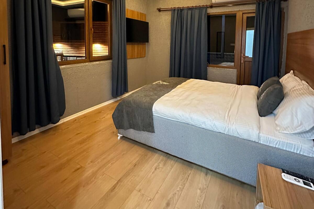 Ein modernes Schlafzimmer mit einem großen Bett, Holzboden und einer Deckenleuchte.
