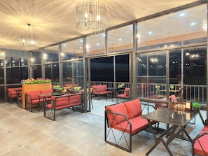 A spacious indoor area with large windows, multiple seating arrangements, and modern lighting fixtures. - Bungaport (Rize)