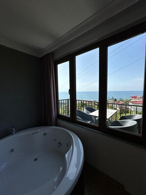 A bathroom with a bathtub and a large window overlooking a balcony with outdoor furniture. - Bungaport (Rize)