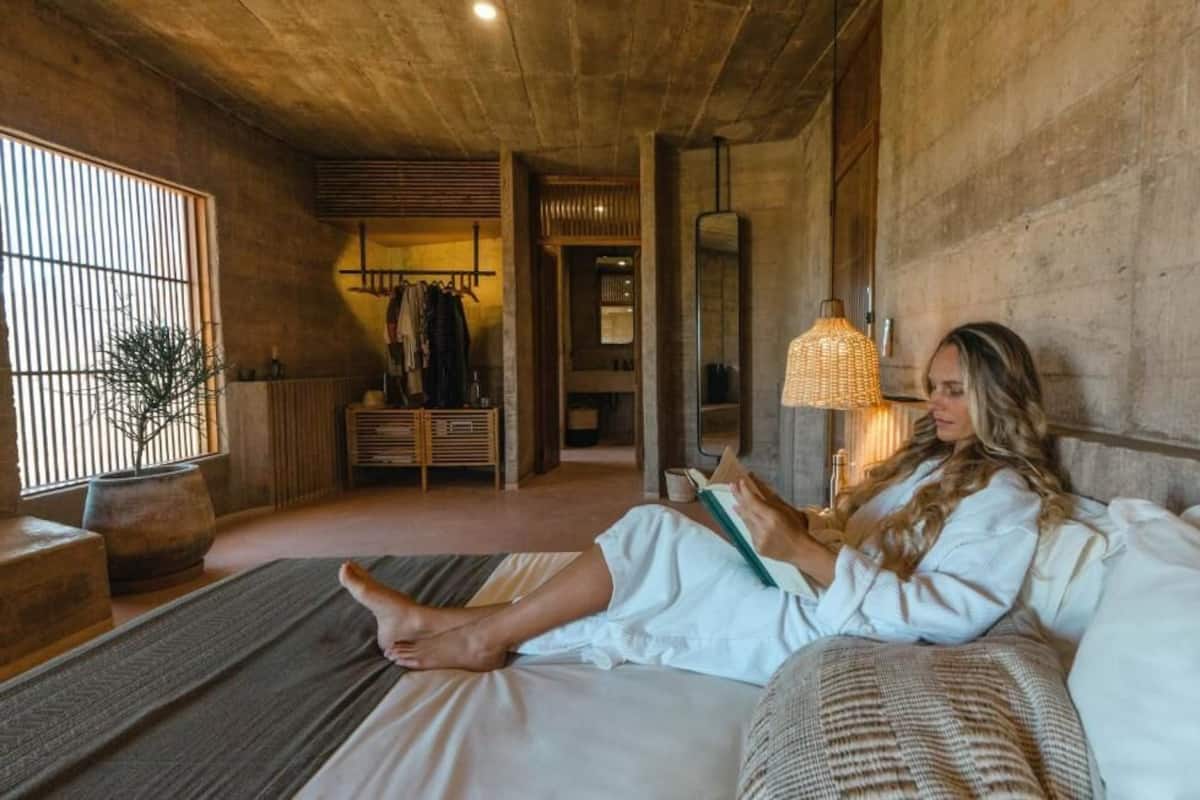 Quarto com cama, um espaço para leitura, guarda-roupa e planta em vaso.