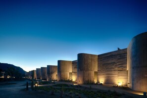 Una serie de estructuras cilíndricas de concreto con entradas iluminadas, ubicadas en un entorno desértico con vegetación escasa.