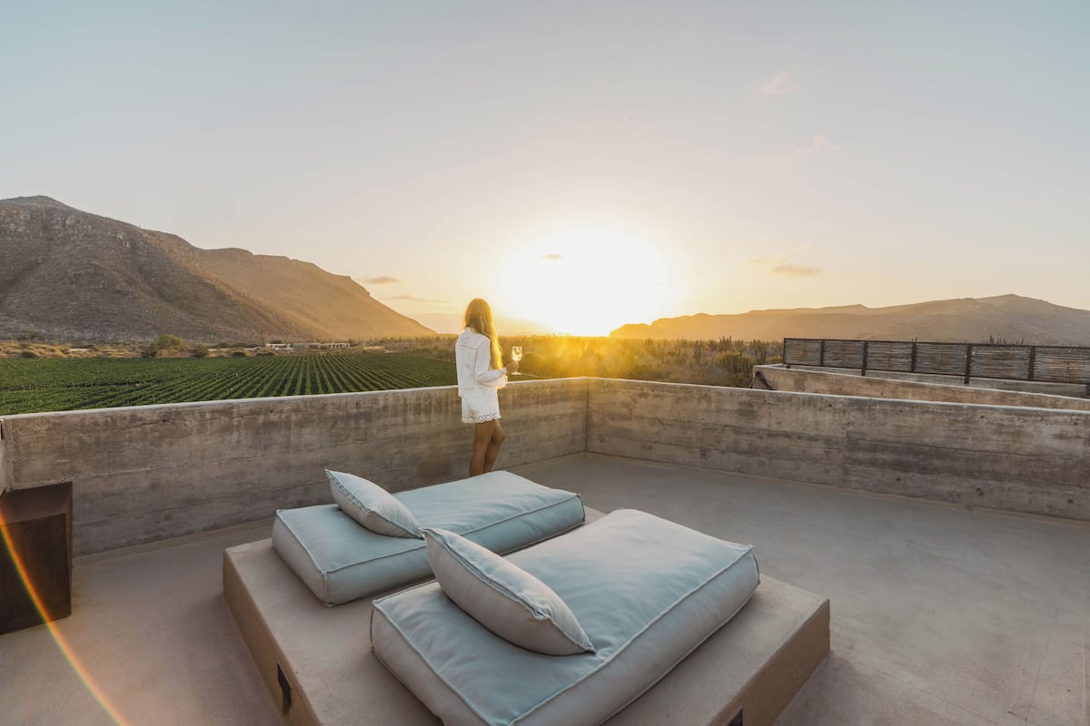 Terraço no telhado com vista para montanhas e um pôr do sol.