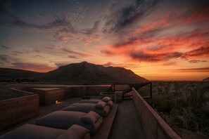 A rooftop terrace with a view of a mountain at sunset, outdoor seating with cushions, and a wooden pergola. - Paradero Todos Santos (Todos Santos)