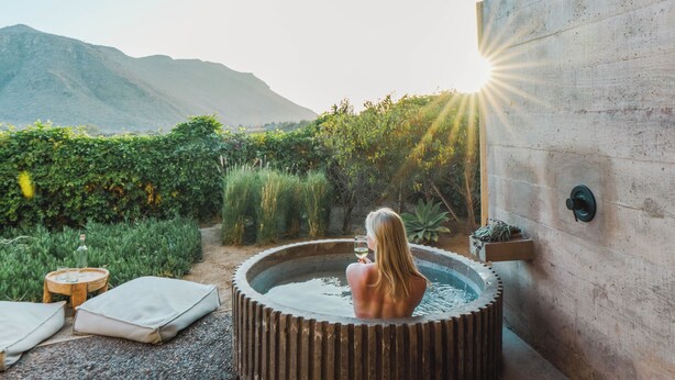 Un jacuzzi bajo una estructura de madera con vista a la montaña.