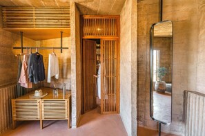 A bathroom with a wooden vanity, a mirror, and a clothing rack with various garments. - Paradero Todos Santos (Todos Santos)