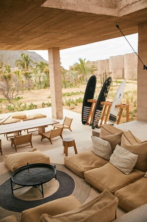 Un espacio al aire libre con mesa, sillas, un sofá y tablas de surf.