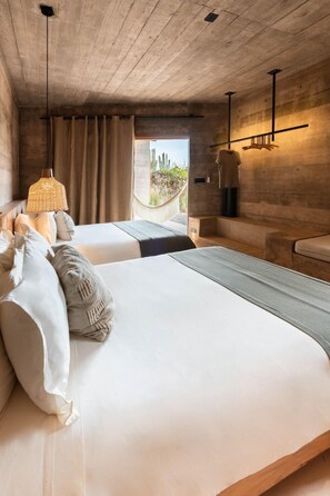 A modern bedroom with a large bed, a hanging light fixture, and a view of the outdoors. - Paradero Todos Santos (Todos Santos)
