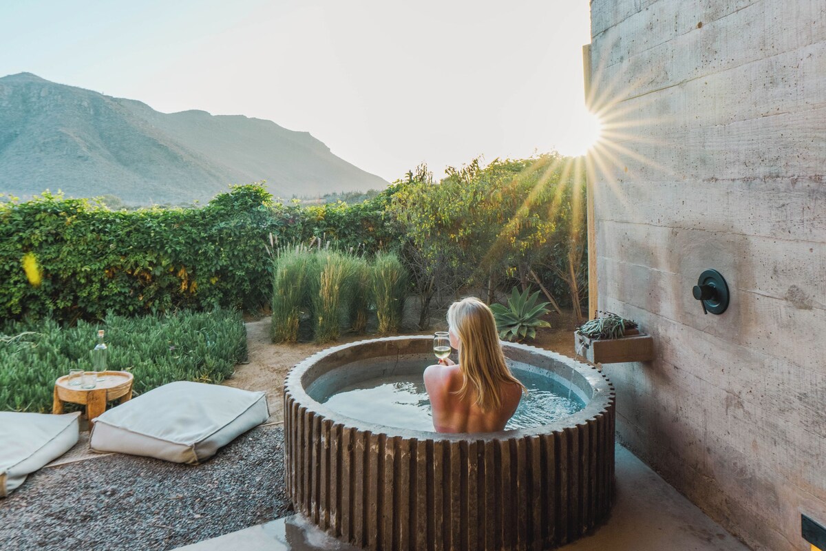 Een hottub onder een houten constructie, met uitzicht op een berg.
