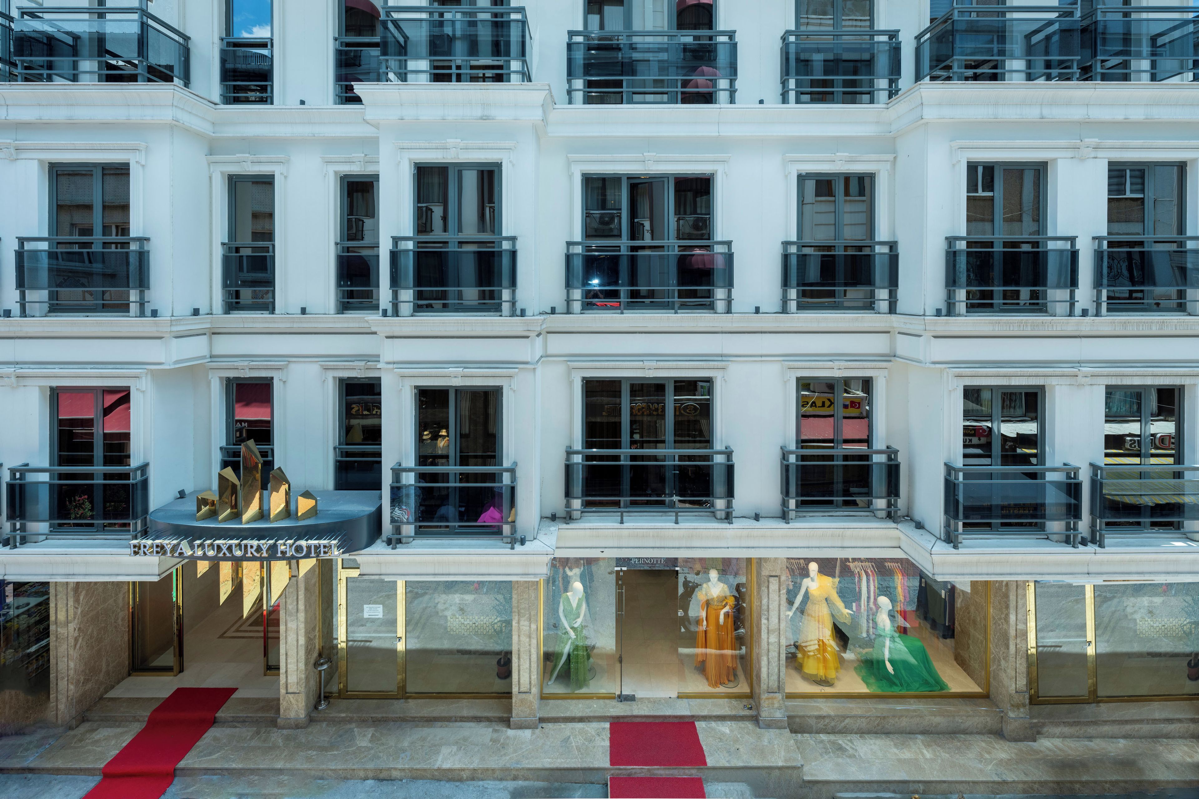 A multi-story hotel with a grand entrance, large windows, and a red carpet leading to the entrance.