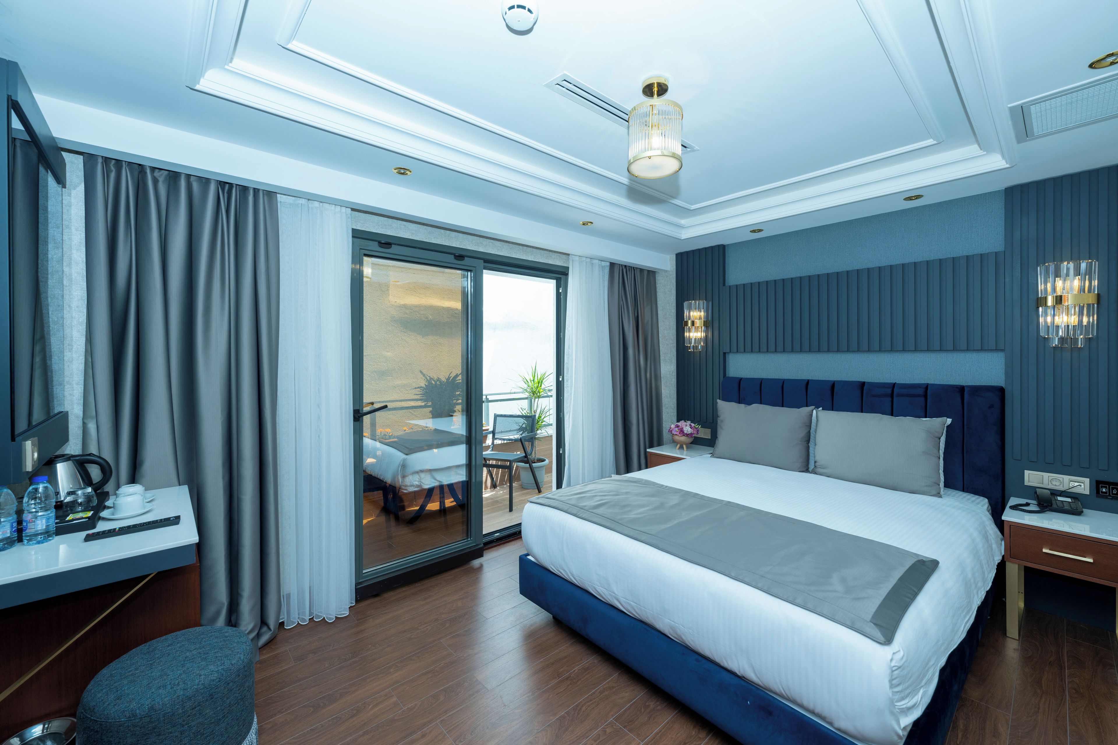 Habitació d'hotel moderna amb un llit gran, un escriptori amb un ordinador, una cadira i vistes a l'exterior.