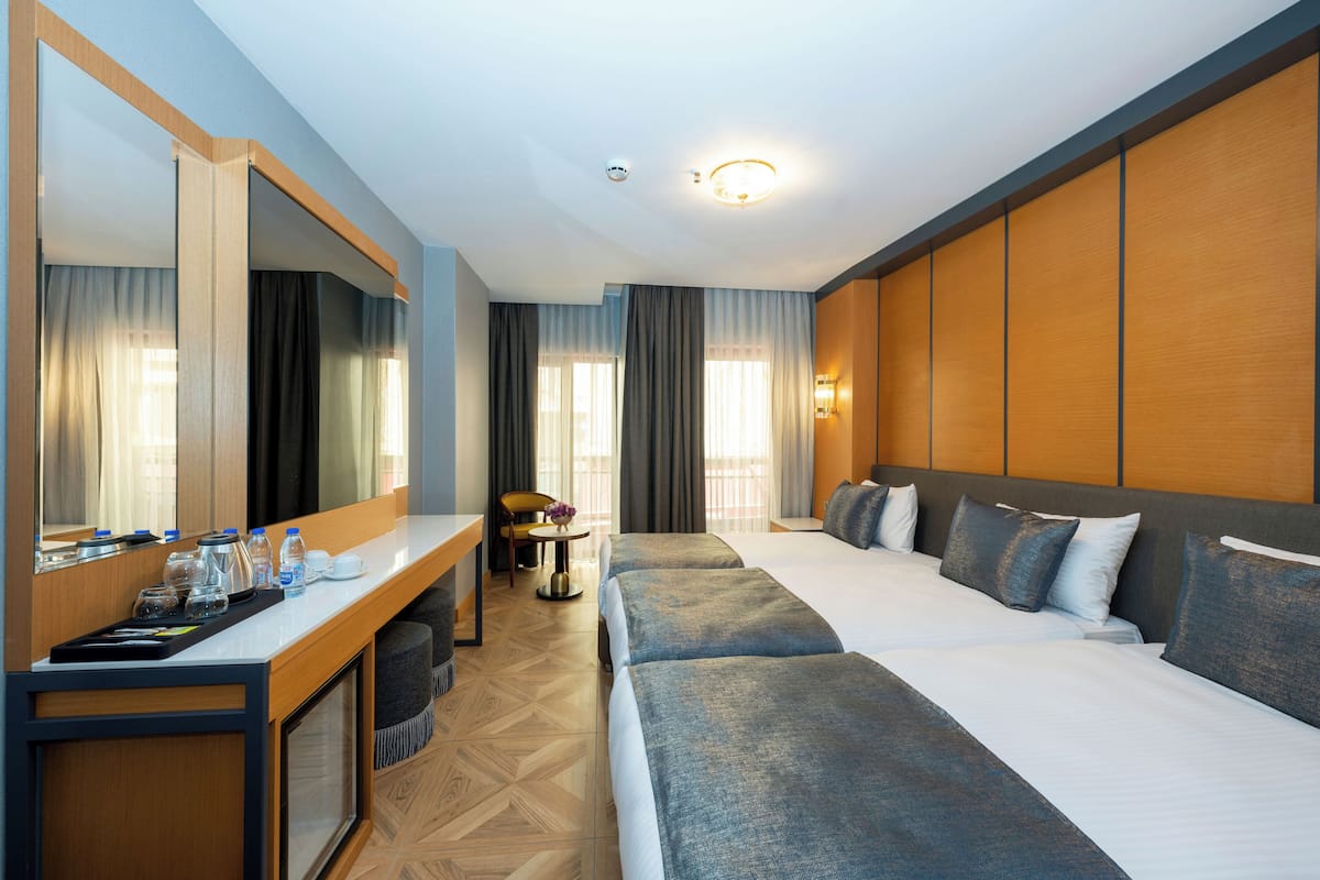 Habitación de hotel con una cama grande, un escritorio con silla, un espejo y vistas al exterior.