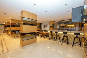 A modern bar area with a high counter, stools, and a seating area with tables and chairs.