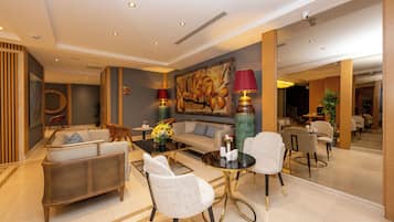 A spacious lobby with a sofa, chairs, a coffee table, and a large painting on the wall.