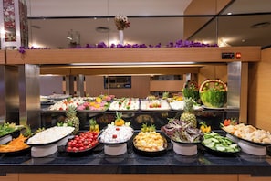 Buffet com diversos alimentos e um vaso decorativo no balcão.