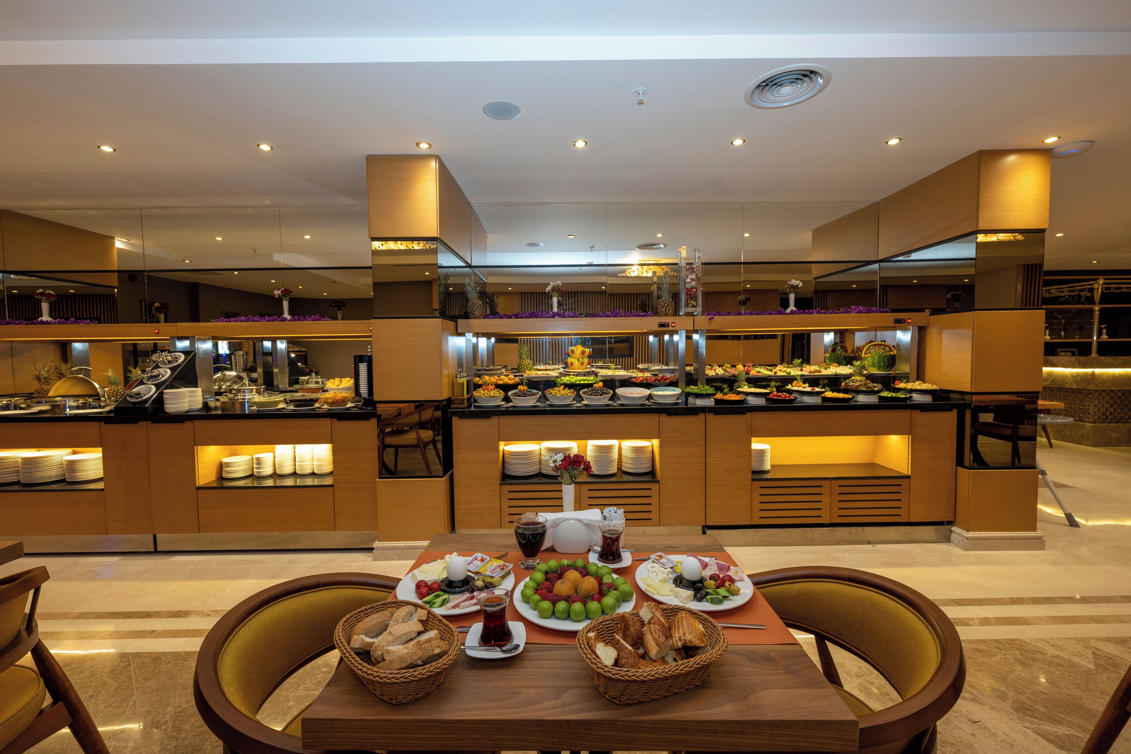 A buffet setup with various food items and a table with plates and baskets.