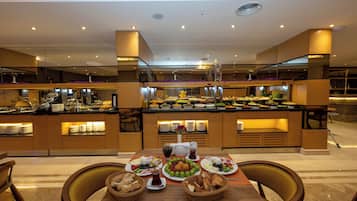 A buffet setup with various food items and a table with plates and baskets.
