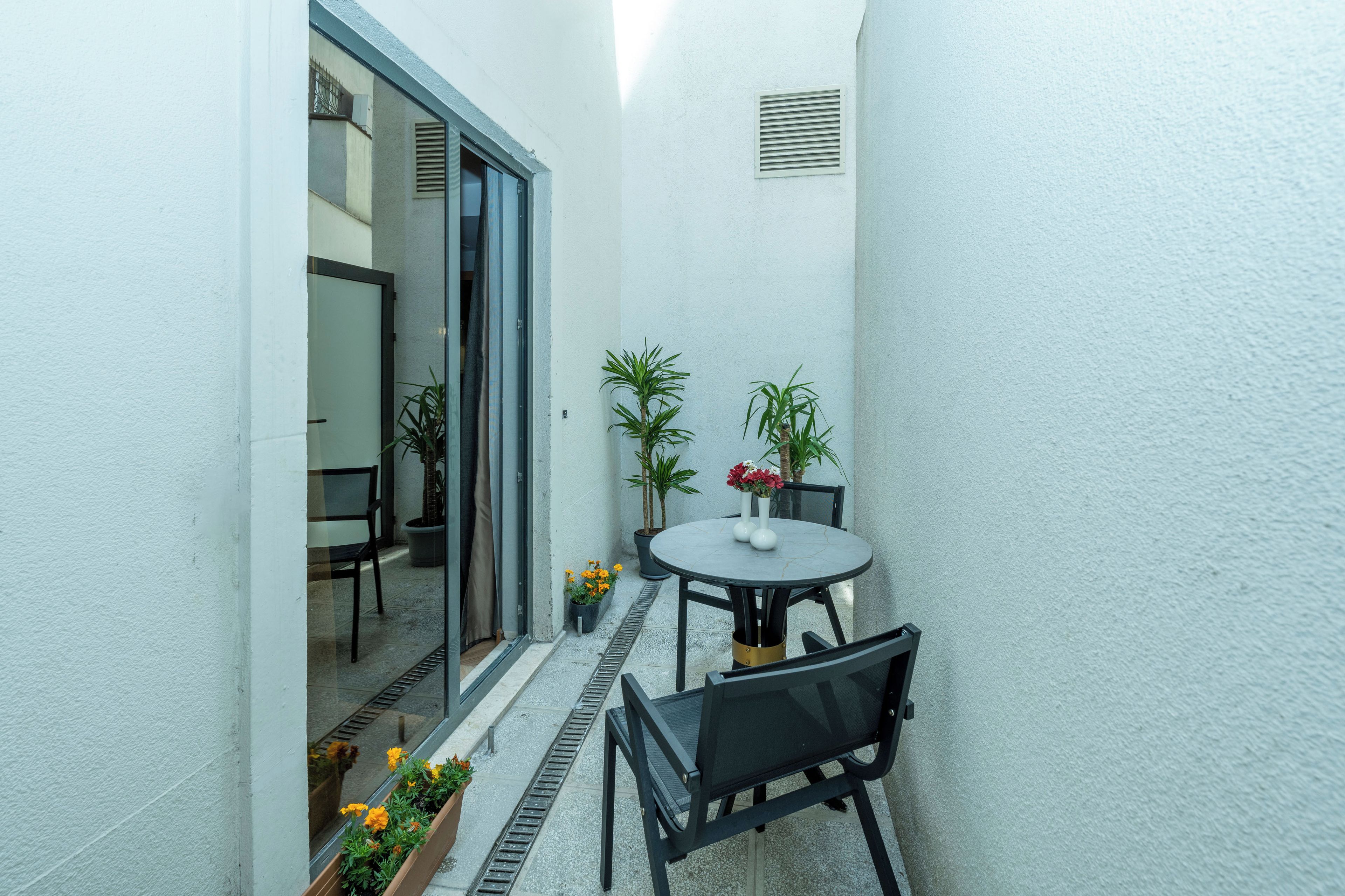 A small patio with a round table, two chairs, and potted plants.
