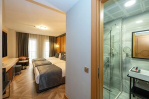 A hotel room with a desk, two beds, a shower area, and a bathroom with a mirror and sink. - Freya Hotel (Istanbul)