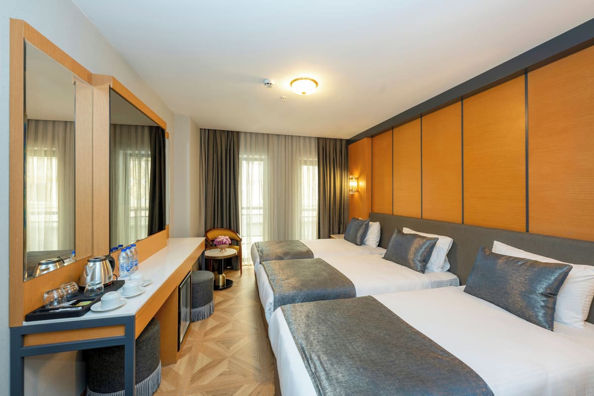 Habitación de hotel con dos camas, un escritorio con espejo, una mesita con silla y un espejo grande.