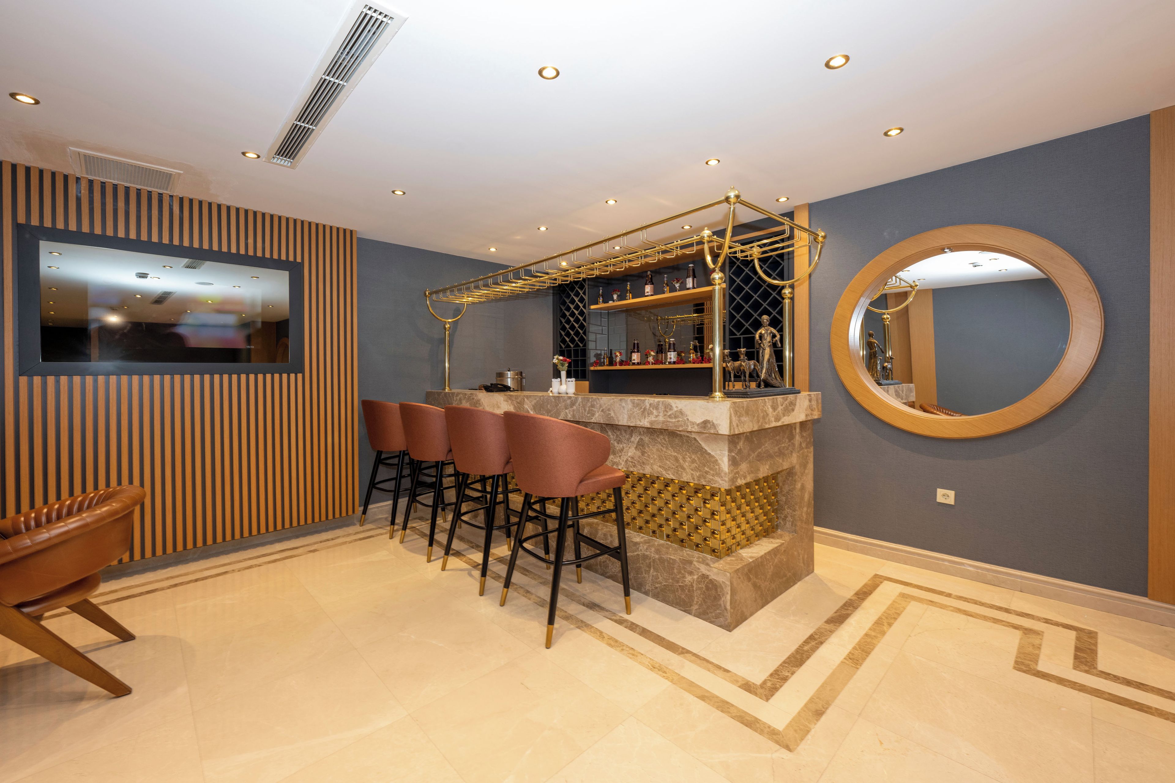 Een bar met krukken, een televisie en een decoratieve spiegel.