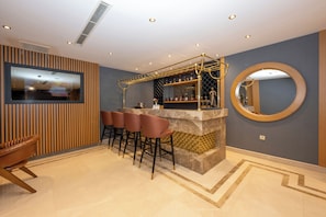 A bar area with stools, a TV, and a decorative mirror. - Freya Hotel (Istanbul)