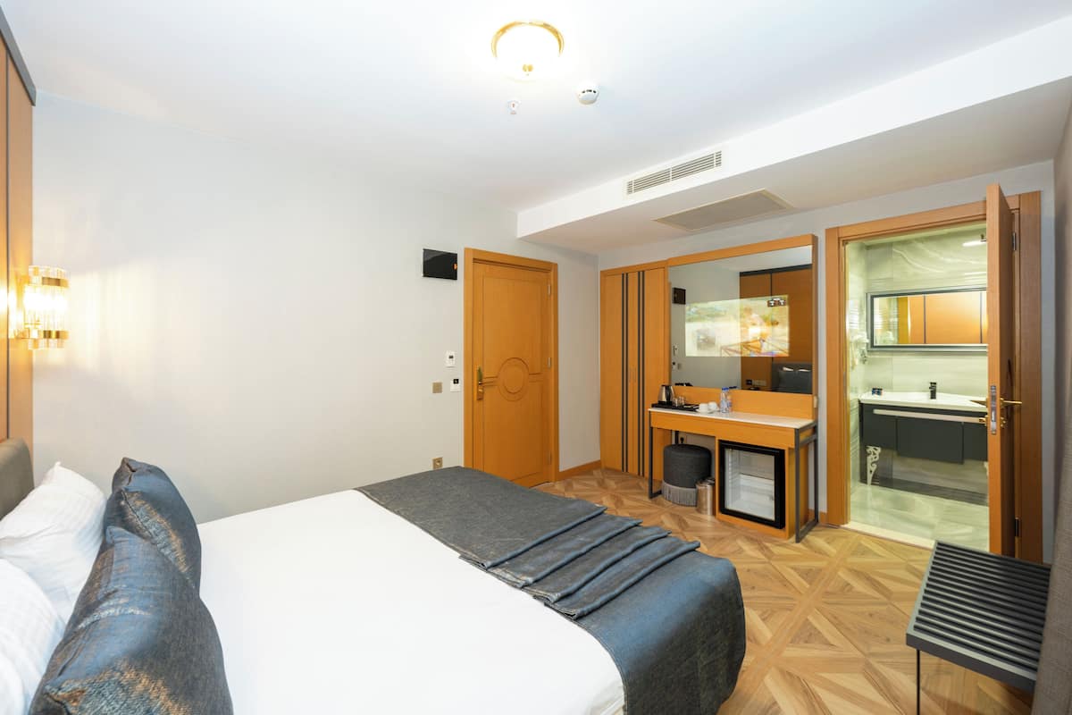 Una habitación de hotel con cama, escritorio y kitchenette.