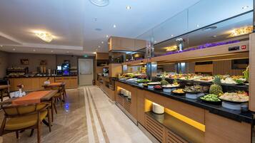 A modern hotel lobby with a buffet area featuring a variety of food options.