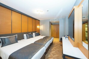 A hotel room with a large bed, a desk, and a mirror.