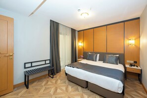 A hotel room with a bed, a bench, a nightstand, and a wooden wardrobe. - Freya Hotel (Istanbul)