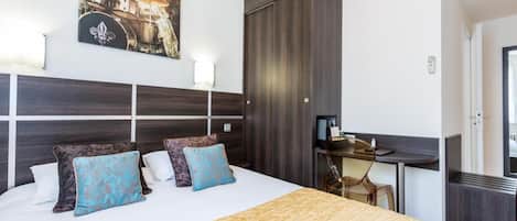 Une chambre d’hôtel avec un grand lit, un bureau, une armoire et un tableau au mur.