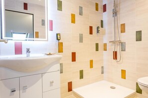 Un baño con lavamanos blanco, espejo y ducha.