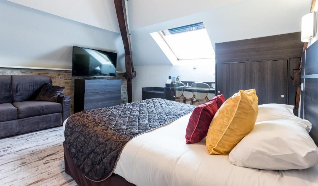 Un dormitorio con cama, televisor, escritorio y ventana.
