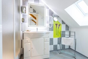 A modern bathroom with a skylight, a white sink, a mirror, and a towel rack.