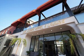Das Äußere des LA AZURE HOTEL & LOUNGE mit einem einladenden Eingang, großen Fenstern und Palmen.