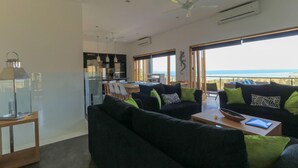 A modern living room with a sofa, a dining table, and a view of the ocean. - Villa K by Zuzu (Selong Belanak)