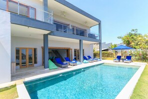 Ein modernes, zweistöckiges Haus mit Schwimmbad, Außenbereich und Balkon.