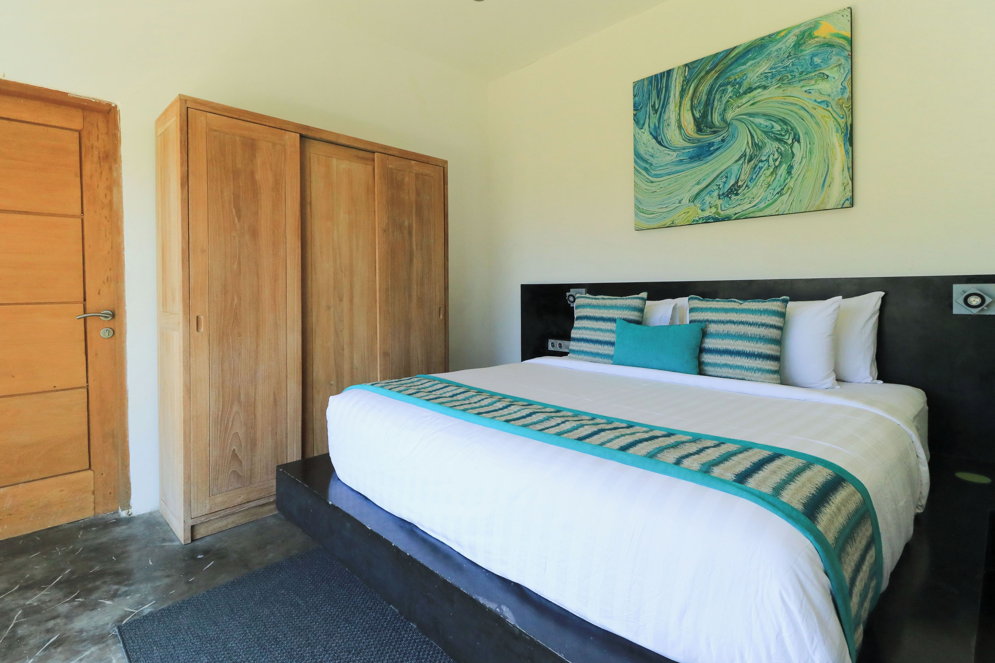 Quarto com cama, guarda-roupa de madeira e uma pintura na parede.